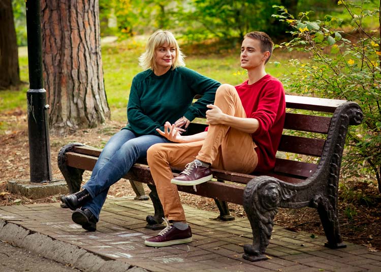 woman talking to teenage son on park bench - your teen